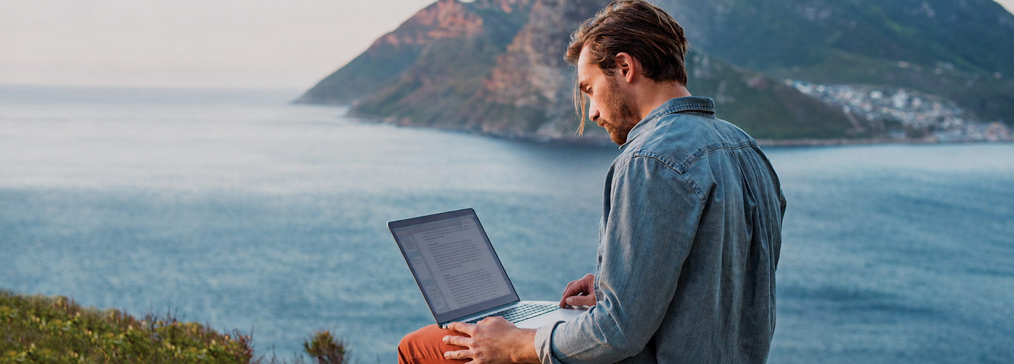 Man using laptop near the ocean